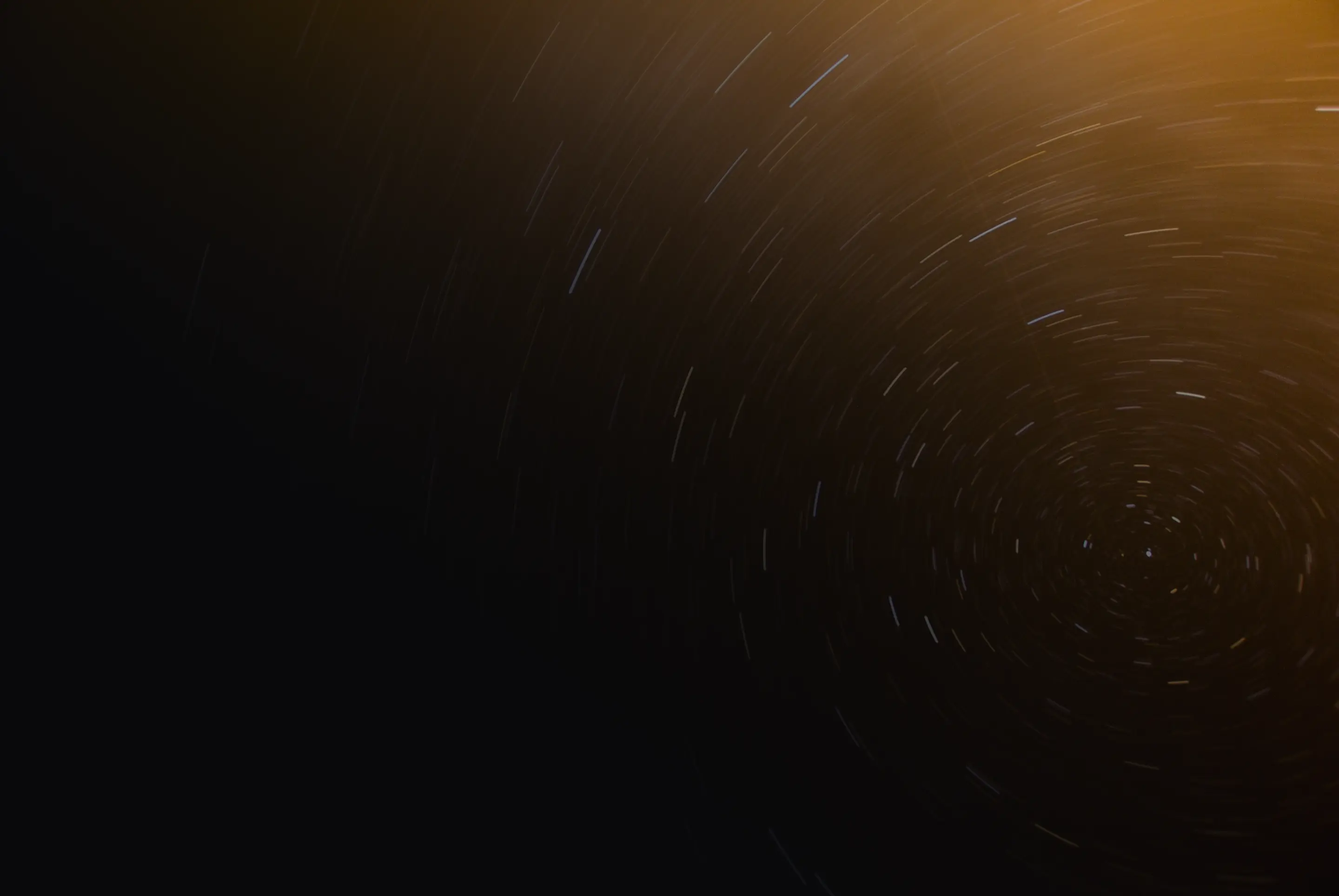 Long-exposure photograph of the night sky showing star trails swirling in circular motion.